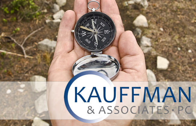 compass in a hand with logo of kauffman and associates