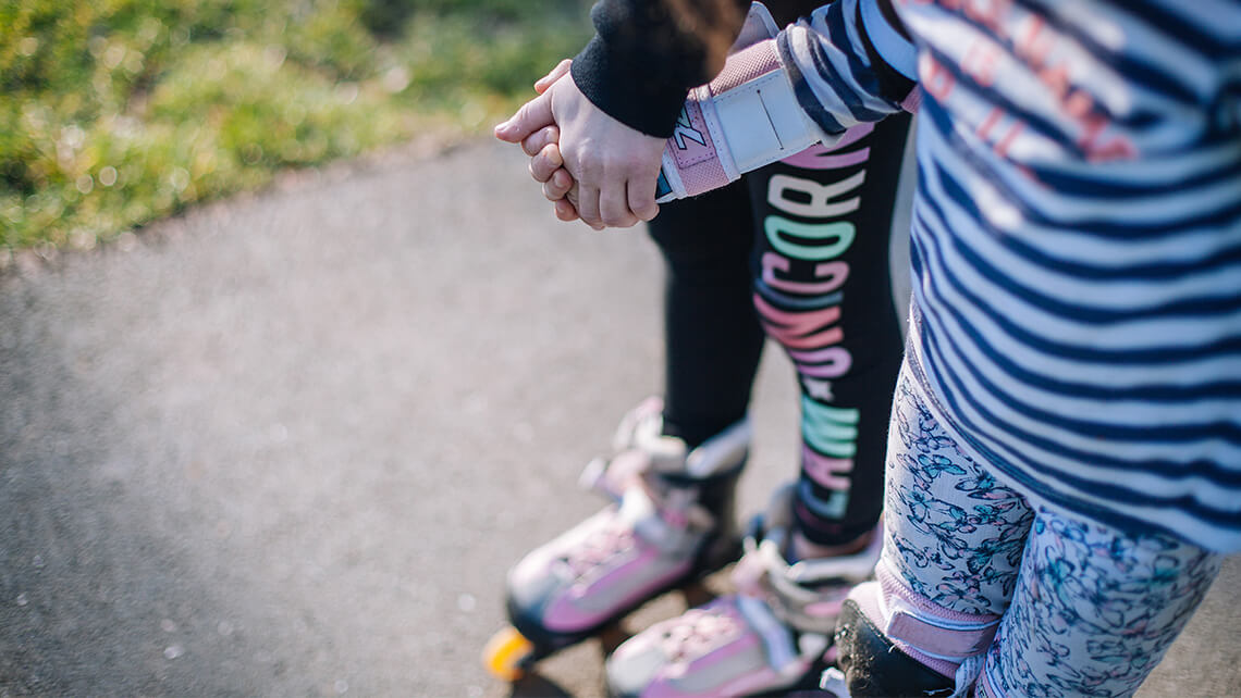 two young girls on roller skates holding hands