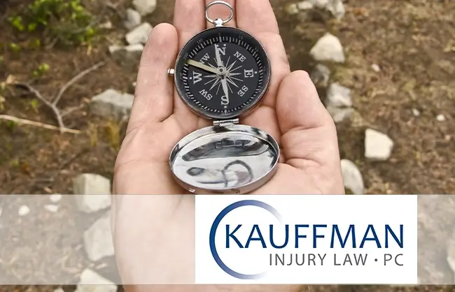 compass in a hand with logo of Kauffman Injury Law